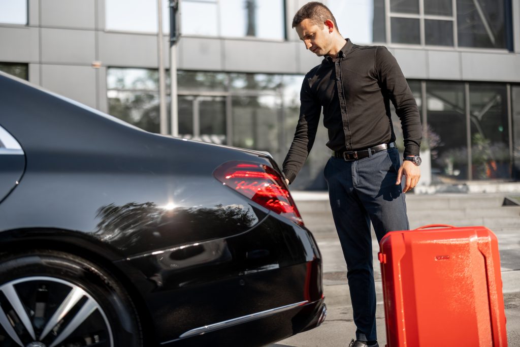 Ovova airport taxi driver assisting with luggage outside terminal for a pre-booked transfer