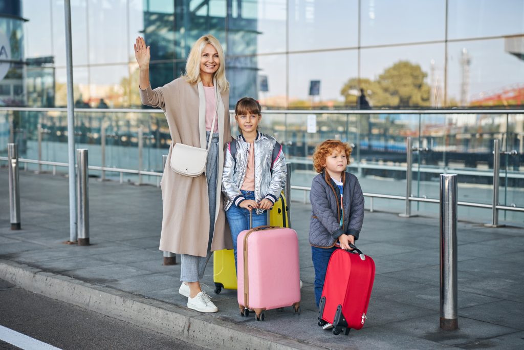 Family waving goodbye outside airport after arriving with Ovova airport taxi